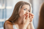Vrouw met acne op haar neus die crèmes gebruikt om puistjes te behandelen.